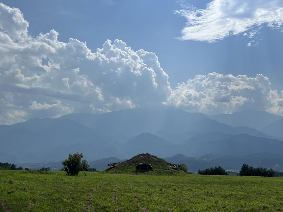 復元された竪穴建物跡と目の前にそびえ立つ赤石山脈